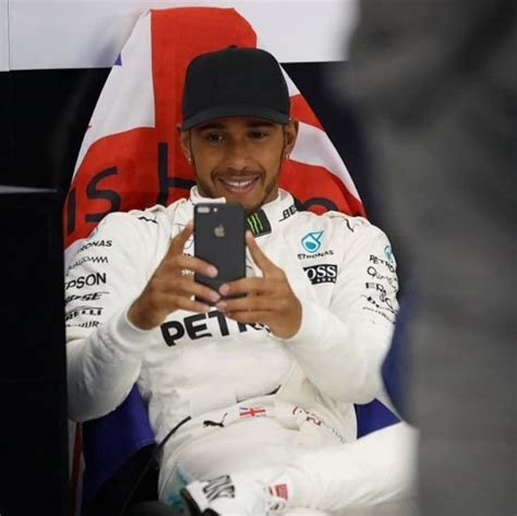 A Man Sitting In Front Of A Flag Holding A Cell Phone