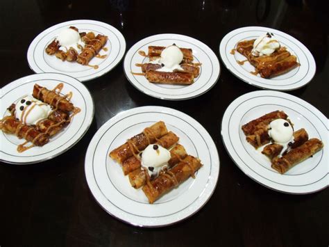 Four White Plates Topped With Waffles And Ice Cream On Top Of A Black Table