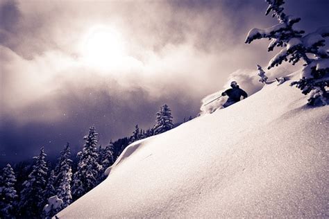 A Person Riding Skis On Top Of A Snow Covered Slope With Trees In The