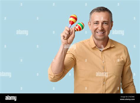 Handsome Mature Mexican Man With Maracas On Blue Background Stock Photo