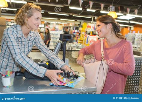 Young Female Store Clerk Serving Purchaser At Cash Desk Stock Photo