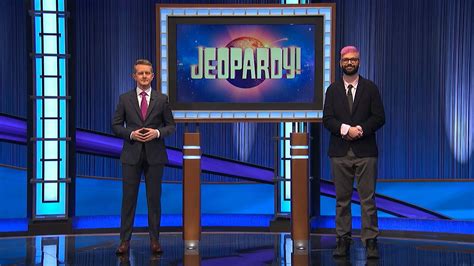 Download Two Men Standing In Front Of A Jeopardy Tv Set