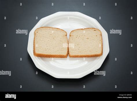 Two Slices Of White Bread Are Side By Side On A White Plate The First