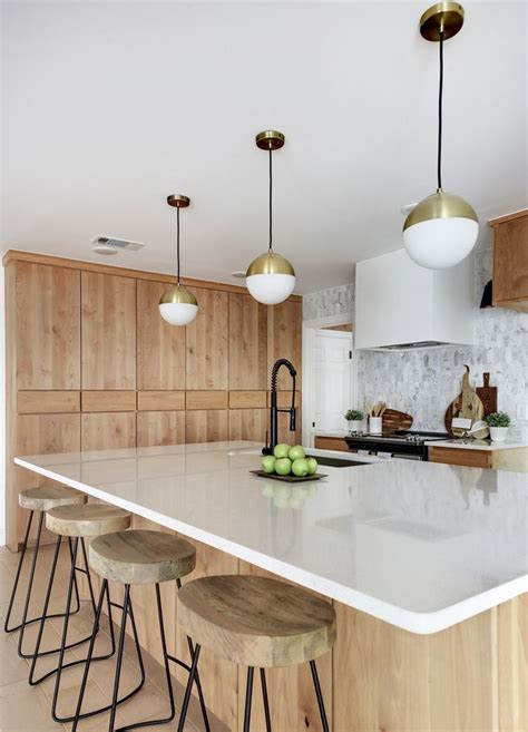 open kitchen with flat front natural alder wood cabinets, light wood floors, globe pendants with ...