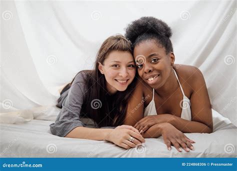 Two Cheerful Lesbian Girls Lying Close To Each Other In Bed Stock Photo