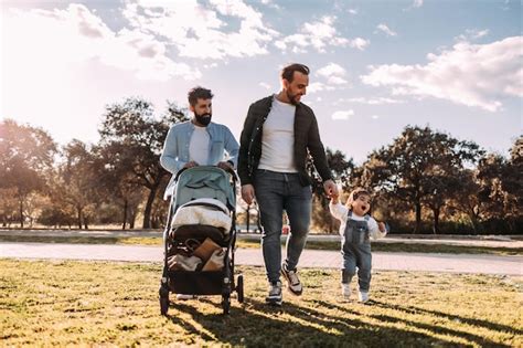Pareja gay masculina caminando con su pequeña hija en el parque al atardecer concepto de familia