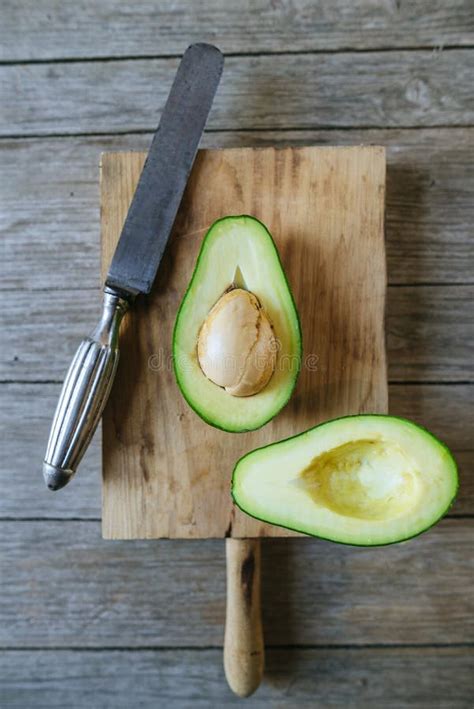 Aguacate Cortado Por La Mitad En La Tabla De Madera Imagen De Archivo