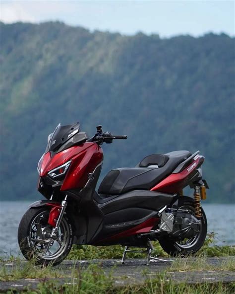 A Red And Black Scooter Parked On The Side Of A Body Of Water