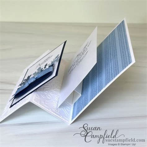 An Open Folded Card On Top Of A White Table With A Blue And White