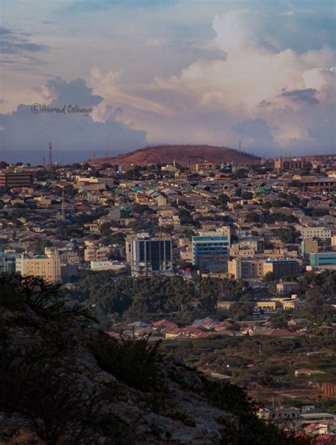 a view of a city from the top of a hill with clouds in the sky