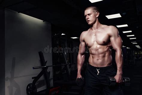 Handsome Strong Athletic Man Pumping Up Muscles With Dumbbells Muscular Bodybuilder With Naked