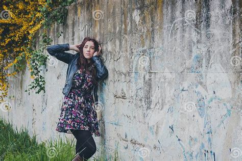 Pretty Girl With Long Hair Leaning Against A Concrete Wall Stock Photo