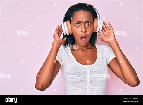 Young African American Woman Listening To Music Using Headphones Afraid