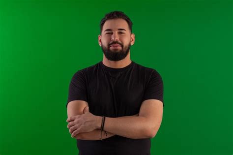 Homem de barba vestindo camisa preta em foto de estúdio fundo verde