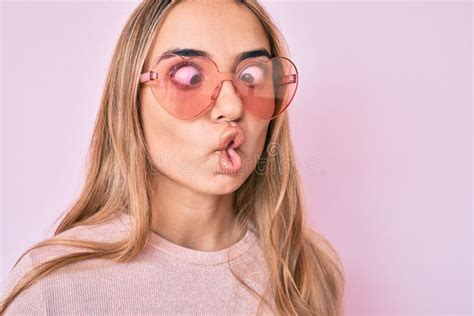 Jeune Belle Femme Blonde Portant Des Lunettes De Soleil En Forme De Coeur Faisant Visage De