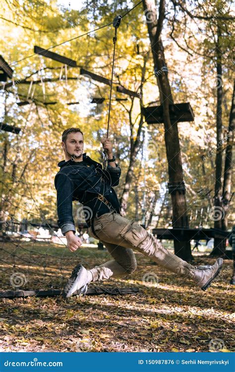 Happy Man Hanging On A Safety Rope Climbing Gear In An Adventure Park