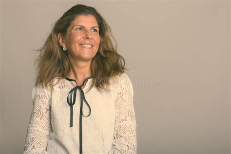 Studio Shot Of Mature Happy Woman Smiling While Thinking And Looking At Distance Stock Image