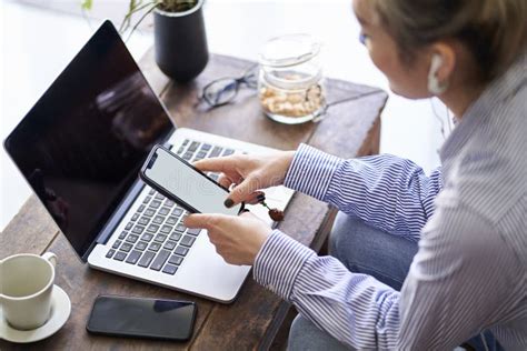 Mature Asian Woman Working From Home Using Mobile Phone And Notebook