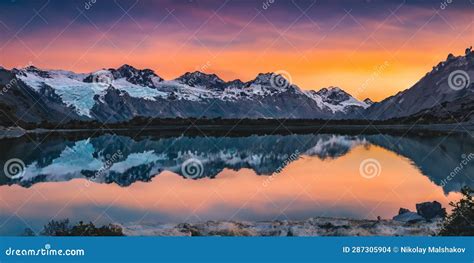 Snow Capped Mountains With A Bright Orange Sunset Sky Reflected In The