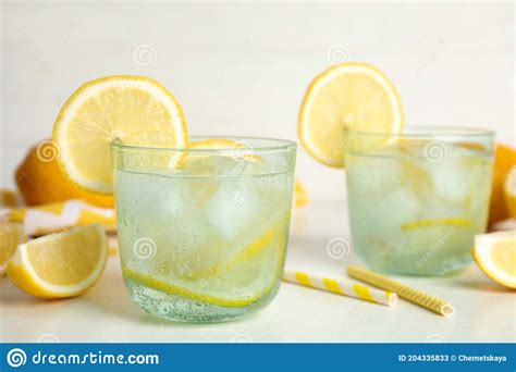 Soda Water With Lemon Slices And Ice Cubes On White Table Space For