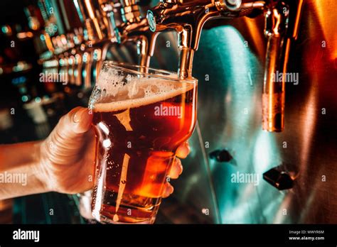 Main de bartender pouring une grande bière blonde au robinet Néon lumineux et moderne les