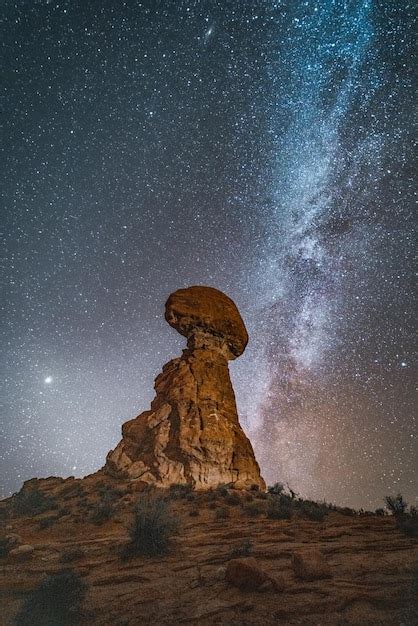 Premium Photo | Balanced rock standing strong against milkyway night ...