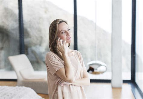 Woman Talking On Cell Phone In Modern Living Room Stock Photo