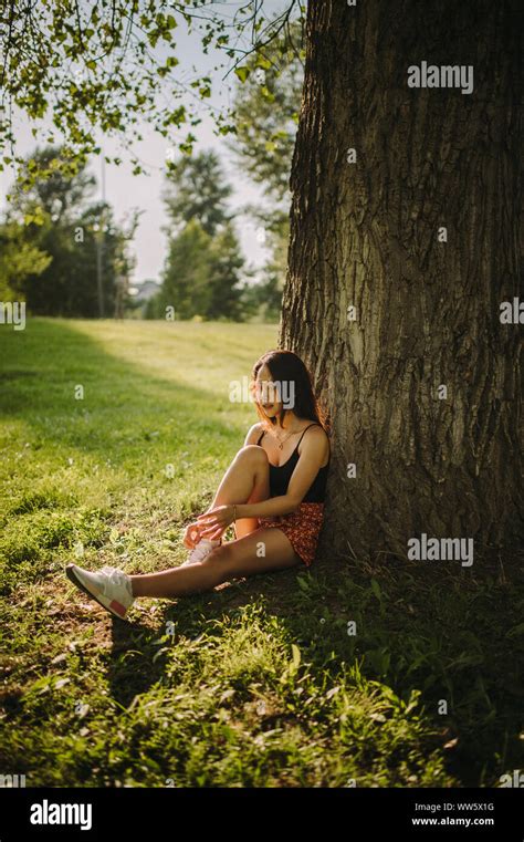 Mujer sentada bajo un árbol fotografías e imágenes de alta resolución