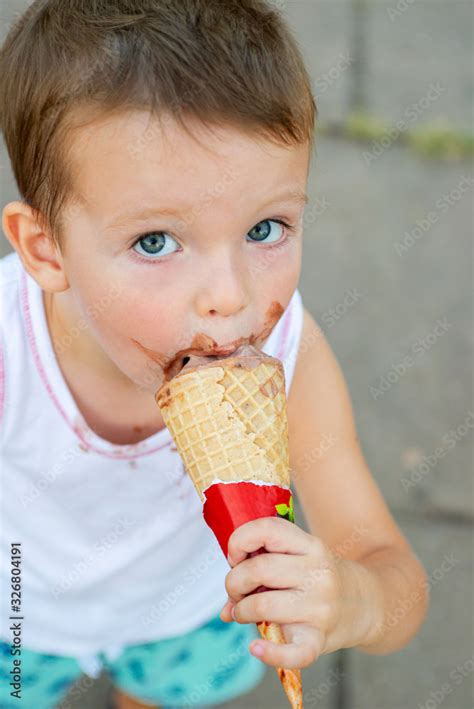 Cute Toddler boy eating ice-cream. Kid with dirty face eating ice cream ...