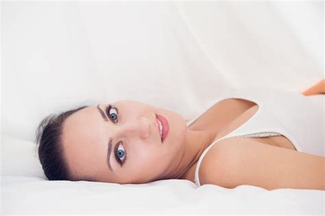 Premium Photo Happy Brunette Lying Under The Sheets Looking
