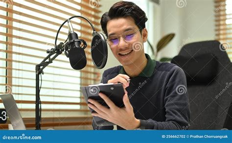 Young Podcaster Using A Microphone And Laptop Computer Recording Audio