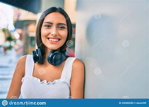 Jovem Latina Sorrindo Feliz Usando Fones De Ouvido Que Se Inclinam Na Parede Imagem De Stock