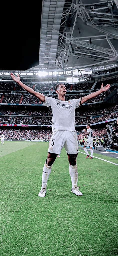 A Man Standing On Top Of A Soccer Field Holding His Arms Up In The Air