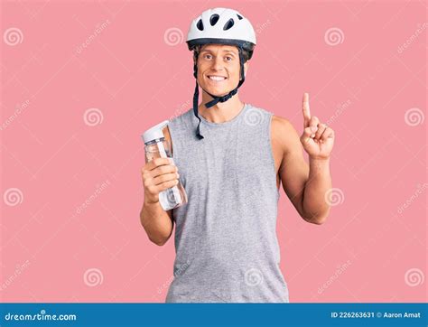 Young Handsome Man Wearing Bike Helmet Holding Bottle Of Water