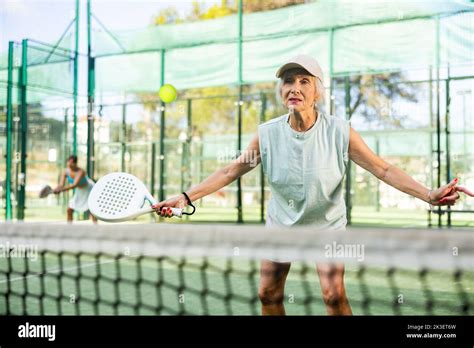 Sporty Mature Woman Padel Player Hitting Ball With A Racket On Hard