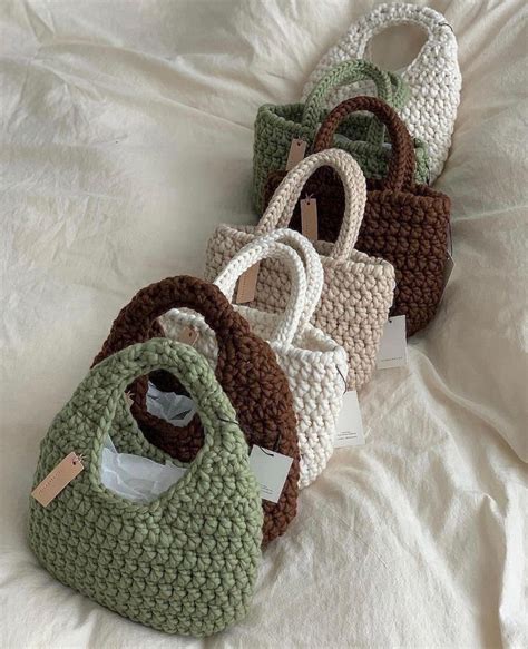 Four Crocheted Purses Sitting On Top Of A White Bed Next To Each Other