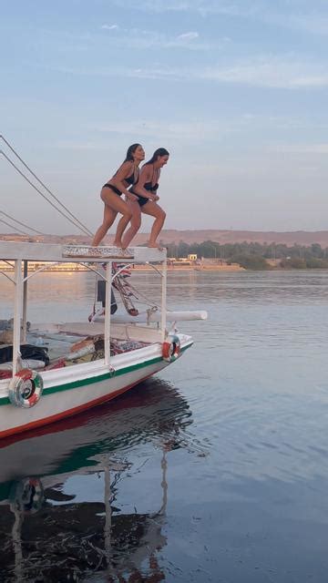 Two Girls In Swimwear Bikini Jumping Off Felucca Boat Into Nile River During Sunset In Luxor