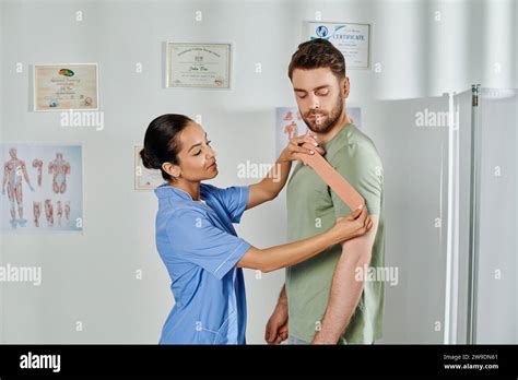 Attractive Young Doctor Consulting Her Handsome Patient About Kinesiological Tapes Healthcare