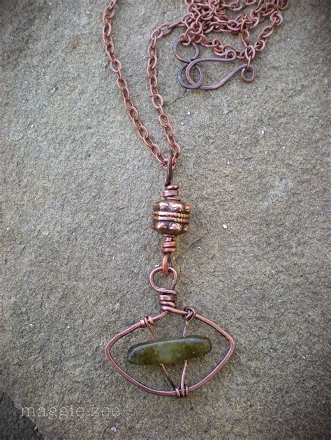 A Wire Wrapped Necklace With A Green Stone Pendant Hanging From Its