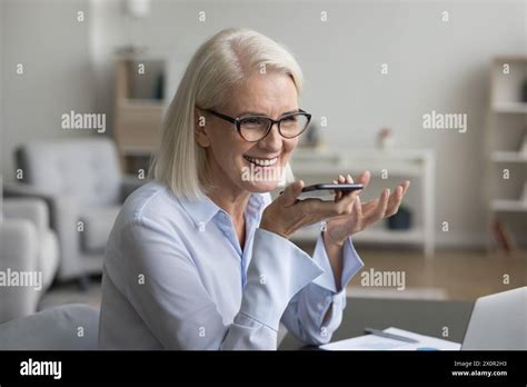 Smiling Mature Businesswoman Speak On Speakerphone Using Mobile Phone