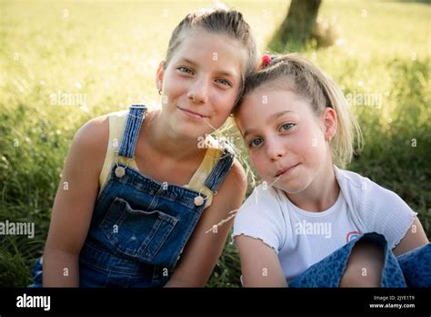 Two Pretty Young Girls Sisters Friends Have Fun Outside In A Meadow In