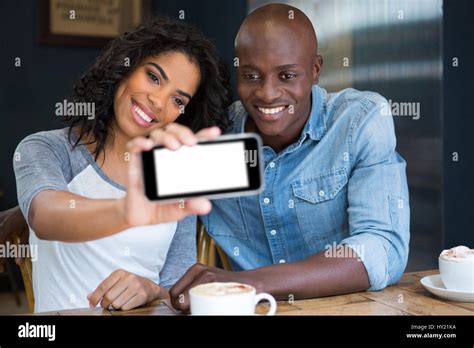 Smiling Multi Ethnic Couple Taking Selfie With Smart Phone In Coffee