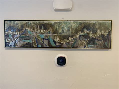 A Painting Hanging On The Wall Next To A White Light Switch In Front Of It