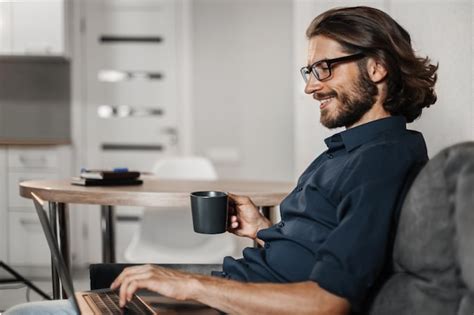 Homem Sorridente Sentado Em Casa No Sof Trabalhando No Laptop E