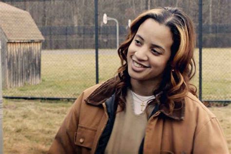 A Woman Standing In Front Of A Fence Smiling