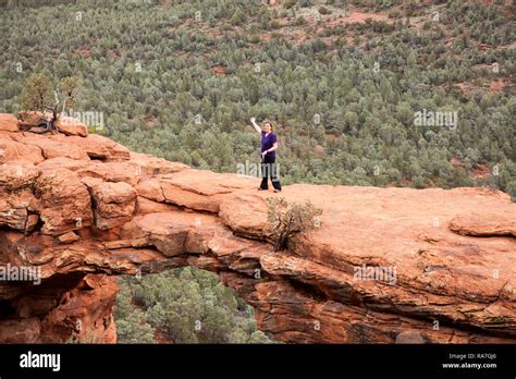 Woman Walking Across Natural Rock Arch Called Devils Bridge In Sedona