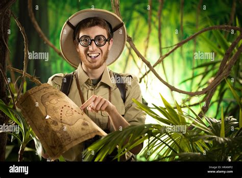 Sonriente Joven Explorador En La Selva Con Gafas Gruesas Sosteniendo Un Mapa Fotografía De Stock