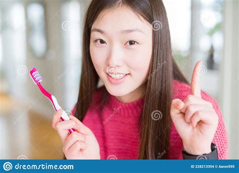 Beautiful Asian Woman Holding Toothbrush Surprised With An Idea Or