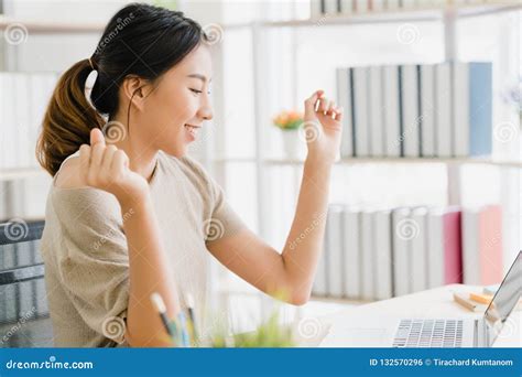 Beautiful Young Smiling Asian Woman Working Laptop On Desk In Living