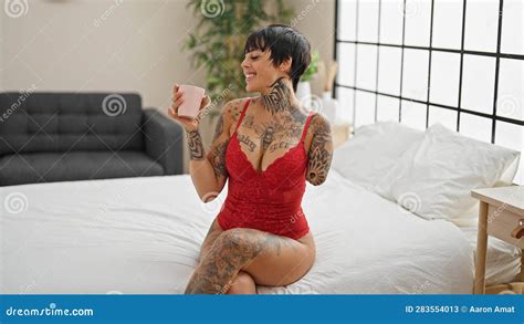 Hispanic Woman With Amputee Arm Wearing Lingerie Sitting On Bed